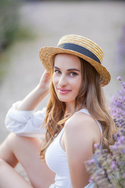 Beautiful young woman in the sunset light. Portrait of a beautiful woman in blooming lavender. - Foto, imagen
