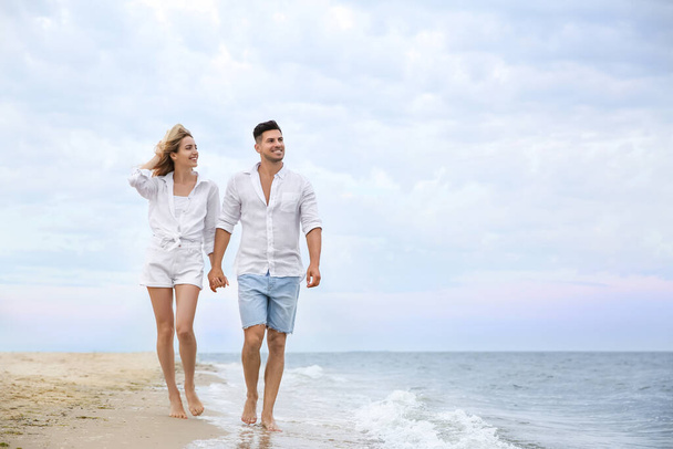 Happy couple having romantic walk on beach. Space for text - Φωτογραφία, εικόνα
