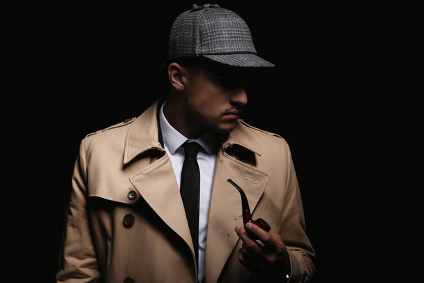 Old fashioned detective with smoking pipe on dark background - Foto, Imagem