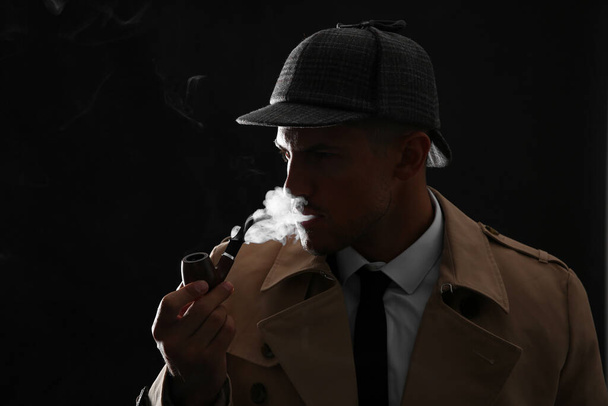 Old fashioned detective smoking pipe on dark background - Foto, afbeelding