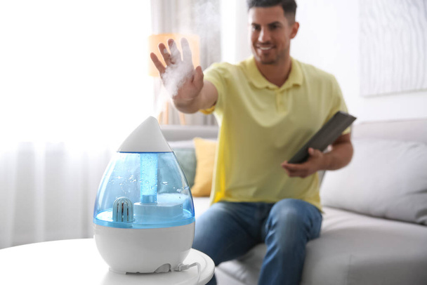 Man near modern air humidifier at home - Zdjęcie, obraz