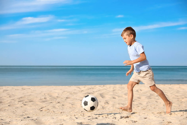 Cute little boy playing with football ball on sandy beach - Fotoğraf, Görsel