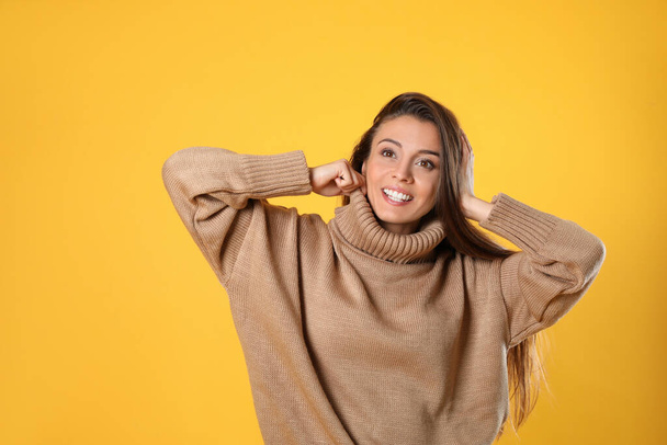 Young woman in stylish brown sweater on yellow background - Photo, image