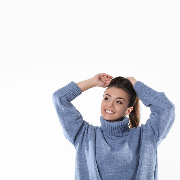 Young woman in stylish blue sweater on white background - Zdjęcie, obraz