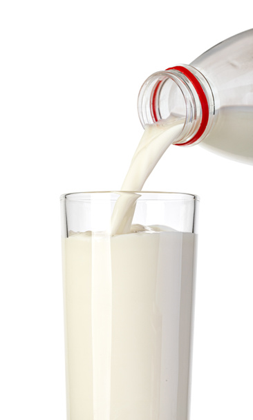 χύνοντας γάλα από τη φιάλη σε ένα ποτήρι που απομονώνεται σε λευκό φόντο - Φωτογραφία, εικόνα
