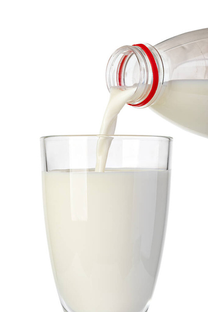 χύνοντας γάλα από τη φιάλη σε ένα ποτήρι που απομονώνεται σε λευκό φόντο - Φωτογραφία, εικόνα