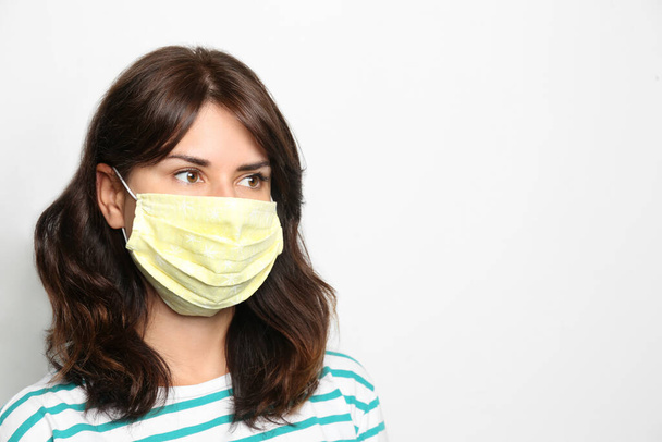 Young woman in protective face mask on light background, space for text - Photo, image