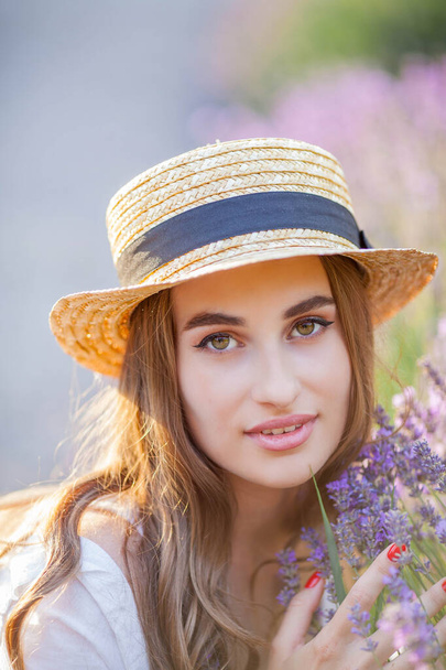 Beautiful young woman in the sunset light. Portrait of a beautiful woman in blooming lavender. - Photo, Image