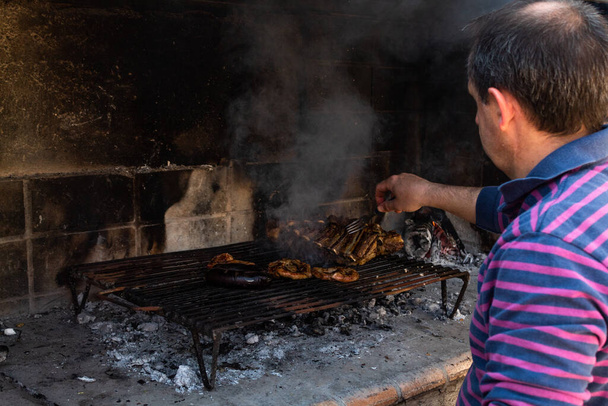 Опытный человек готовит жареное мясо на гриле. - Фото, изображение