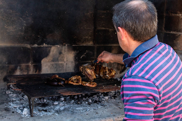 Homme compétent cuisinant une viande rôtie sur son gril. - Photo, image