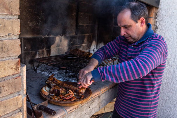 Skillful man cutting meat on wooden dish. - Photo, Image