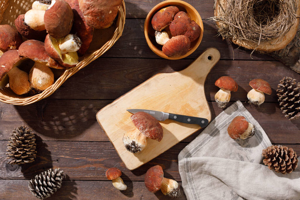 Harvest concept. Wild porcini mushrooms in a handmade wicker basket on a wooden background top view. - Fotó, kép