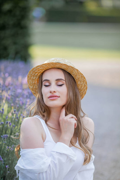 Beautiful young woman in the sunset light. Portrait of a beautiful woman in blooming lavender. - Foto, Imagen