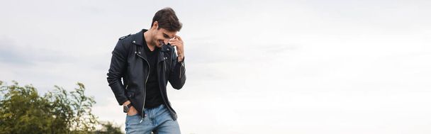 Panoramic shot of man in leather jacket standing outdoors - Valokuva, kuva