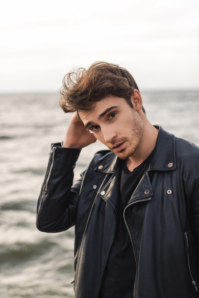 Young man in leather jacket looking at camera near sea  - Foto, immagini