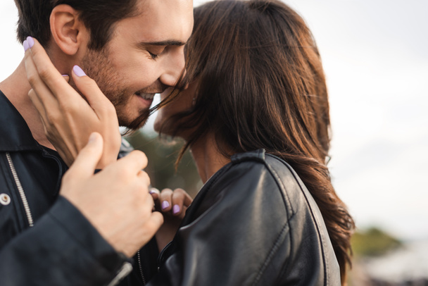 Selective focus of woman in leather jacket touching boyfriend outdoors - Photo, Image