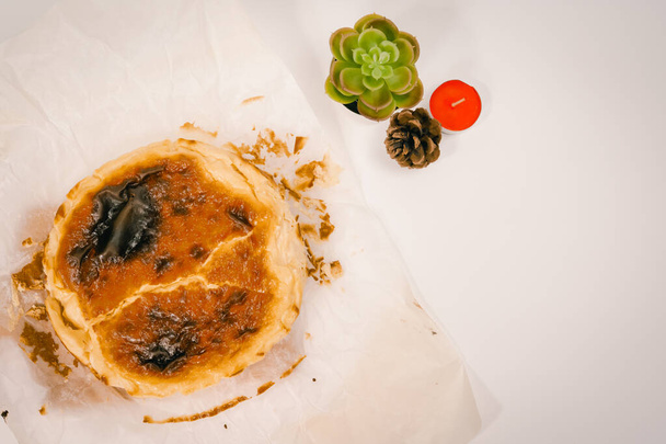 trendikäs kotitekoinen jälkiruoka ja täydentävä ura uudessa normaalissa ylhäältä näkymä baski palanut juustokakku valkoisella taustalla - Valokuva, kuva