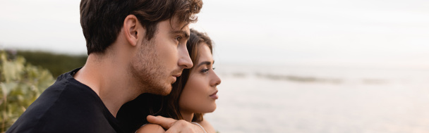 Honlap fejléce férfi ölelés barátnője, miközben nézi a tengert  - Fotó, kép