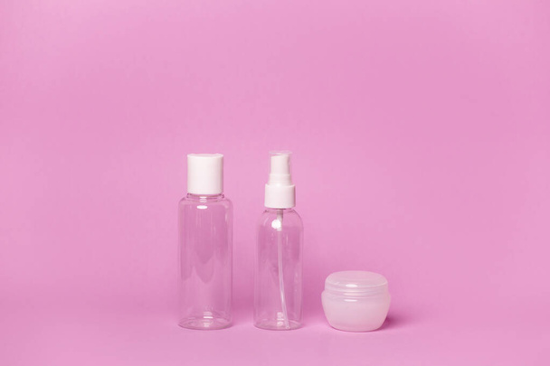 Косметичні пляшки та банки на рожевому фоні
 - Фото, зображення