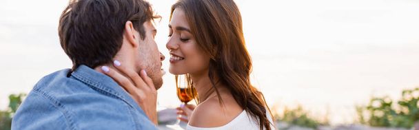Website header of woman holding glass of wine and kissing boyfriend on beach  - Фото, зображення