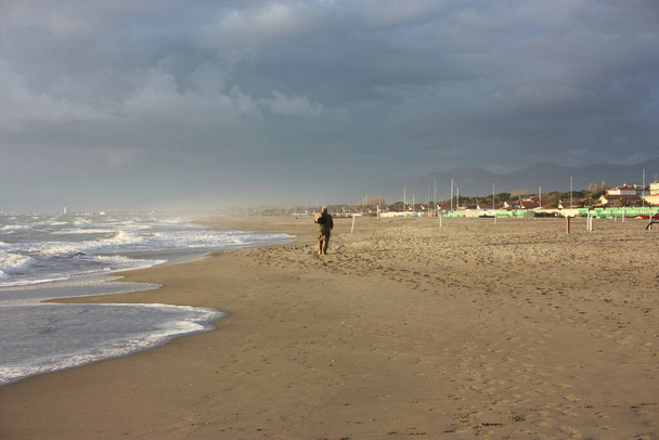 relaxing walks on the sandy beach of Versilia on a sunny day in Italian winter - Photo, Image