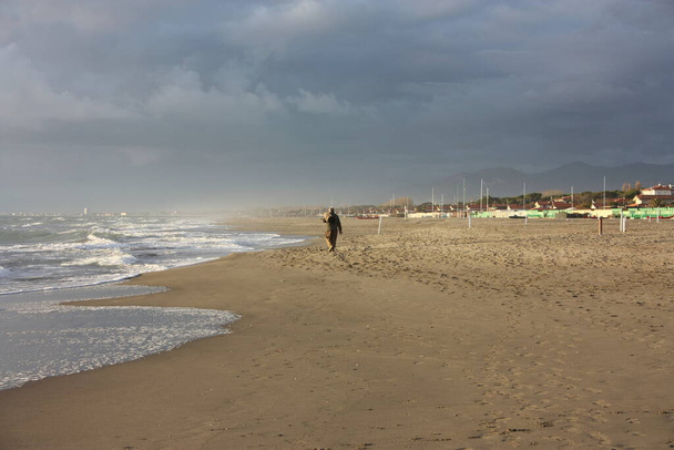 Прогулюючись піщаним пляжем Версилії в сонячний день італійської зими. - Фото, зображення
