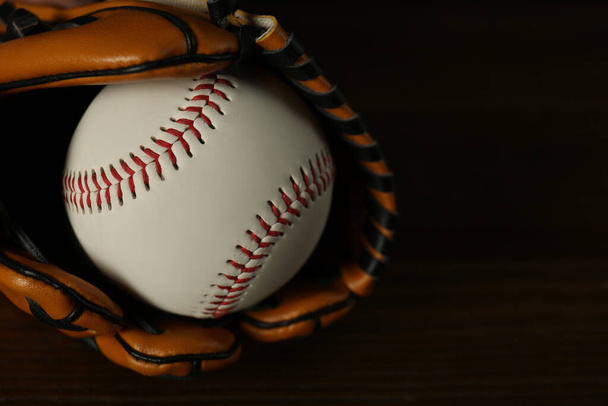 Leather baseball ball and glove on wooden table, closeup - Foto, afbeelding