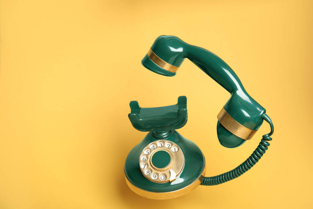 Green vintage corded phone on yellow background - Foto, Bild