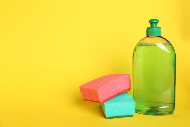 Detergent and sponges on yellow background, space for text - Photo, Image