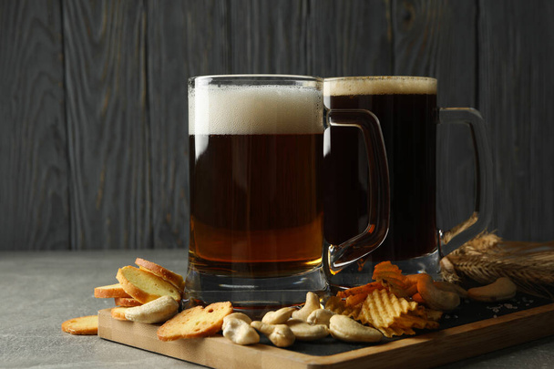 Bière et snacks sur table grise sur fond bois - Photo, image