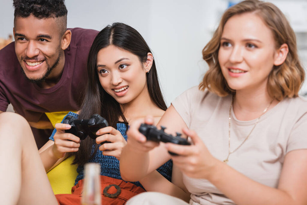 KYIV, UKRAINE - JULY 28, 2020: selective focus of multiethnic friends playing video game during party - Photo, Image