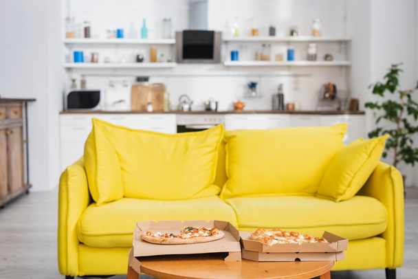 смачна піца на столі біля жовтого дивана в сучасній кухні
 - Фото, зображення