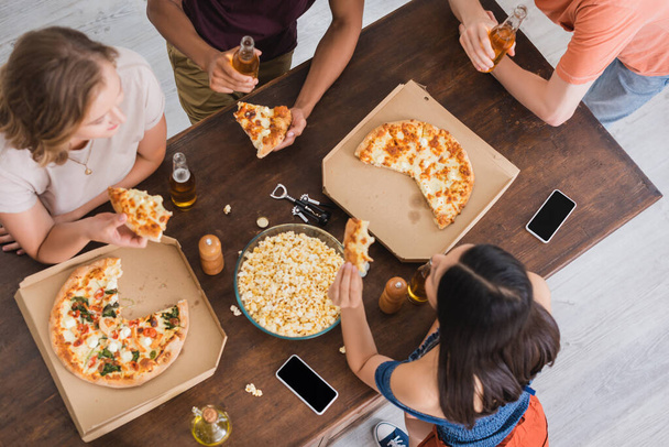 widok z góry wielonarodowych przyjaciół pijących piwo i jedzących pizzę podczas imprezy - Zdjęcie, obraz