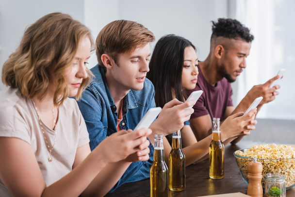 selektivní zaměření multikulturních přátel chatování na mobilních telefonech během párty - Fotografie, Obrázek