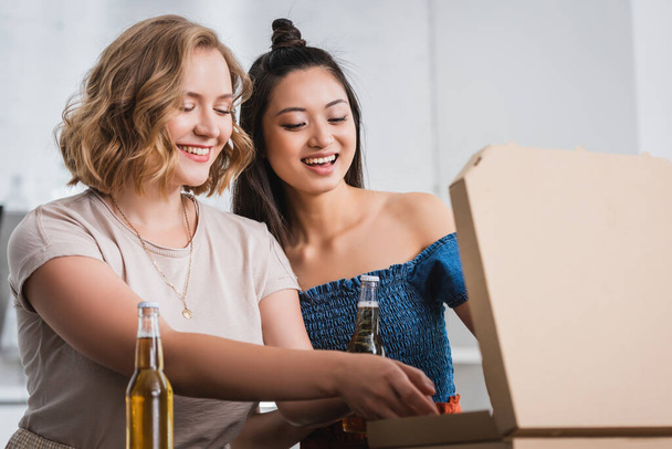 ενθουσιασμένοι πολυεθνικοί φίλοι ανοίγουν κουτί πίτσας κατά τη διάρκεια του πάρτι - Φωτογραφία, εικόνα