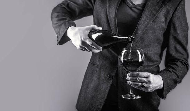 Gourmet drink bottle, red wine glass, sommelier, tasting. Waiter pouring red wine in a glass. Sommelier man, degustation, winery, male winemaker. Red wine is poured from bottle to glass. - Fotó, kép