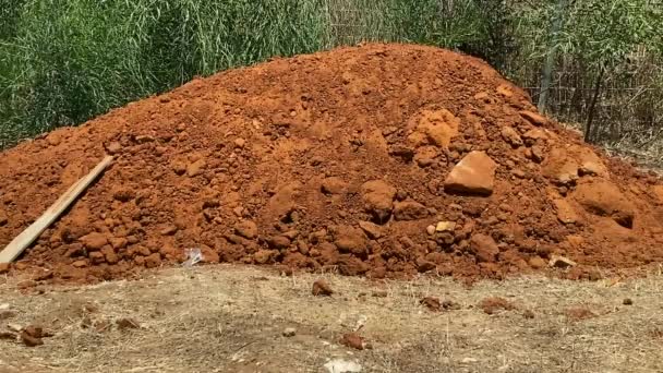 Mountain or pile of red earth on green bush background - Footage, Video