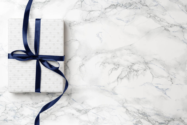 Weihnachten weißes Geschenk mit blauem Band auf Marmor Hintergrund - Foto, Bild
