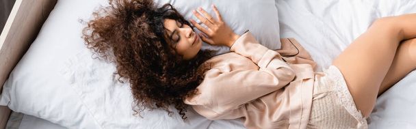 website header of curly woman with closed eyes lying on bed - Foto, afbeelding
