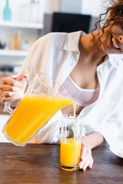 ジュースを持って新鮮なオレンジジュースを注ぐ喜びの女性のクロップドビュー  - 写真・画像