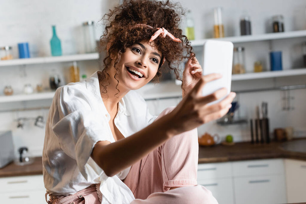 selective focus of excited woman taking selfie on smartphone in kitchen  - Foto, afbeelding