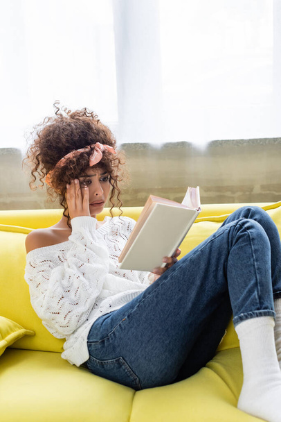 szomorú fiatal nő olvasás könyv a nappaliban  - Fotó, kép