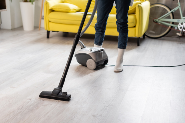 cropped view of woman in socks using vacuum cleaner while cleaning home - Фото, зображення