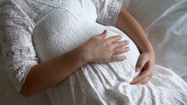 妊娠中の女性は子供の世話をしながら家で幸せを感じています。妊婦のお腹に赤ちゃんを抱えている若い母親。産前産後ケアと女性妊娠の概念. - 映像、動画