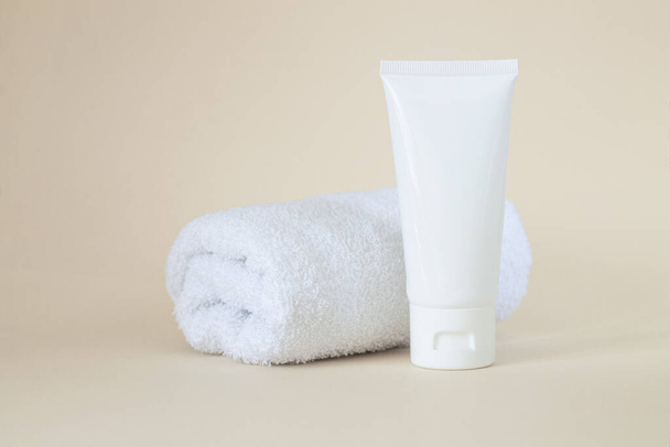 Blanco witte cosmetische tube voor crème, gel, cosmetica, medicijnen of tandpasta naast handdoek - Foto, afbeelding