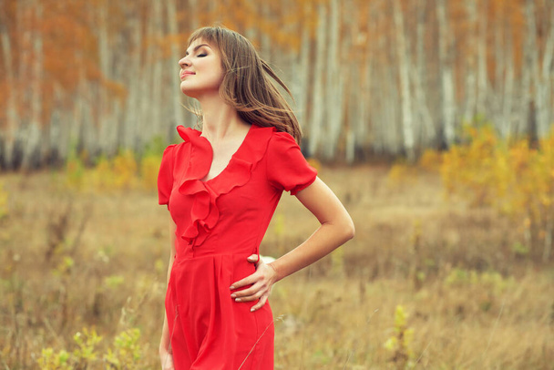 autumn portrait of a beautiful brunette middle aged woman in a red dress - Foto, imagen