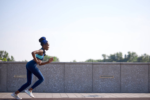 young black fitness woman running in stadium - 写真・画像