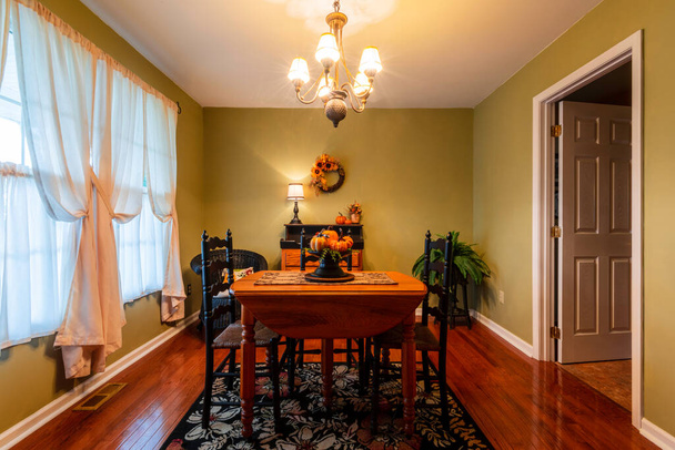 formální jídelna s dubovým stolem a podlahami zdobené na podzim dýňovým slunečnicovým věncem a ananasovým lustrem - Fotografie, Obrázek