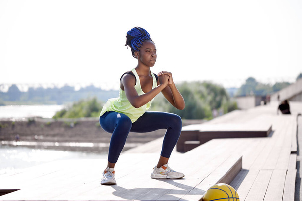 healthy slim afro woman do squats outdoors - Foto, Imagem