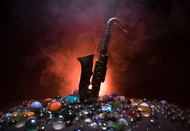 Zenei koncepció. Szaxofon jazz hangszer. Alto arany szaxofon miniatűr színes tónusú fény ködös háttér. Szaxofon hangszer alacsony fényben. Szelektív fókusz - Fotó, kép